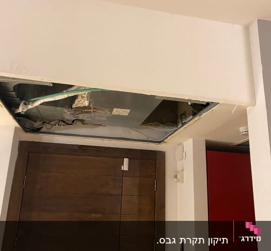 תקרה פתוחה עם צינורות וחוטי חשמל גלויים